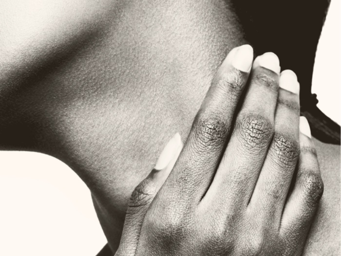 Woman with clear skin gently touching her fingers to her neck